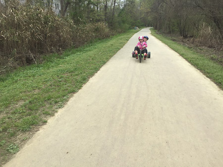 Ella and Penny on the greenway on the green machine